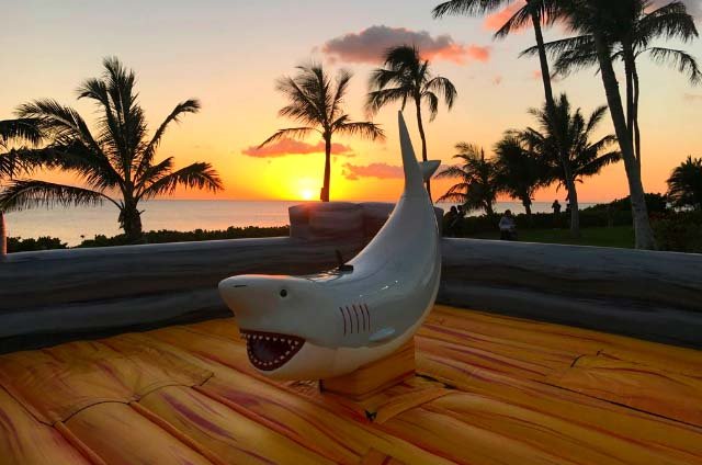 A mechanical shark ride on an inflatable base at an Oahu beach at sunset